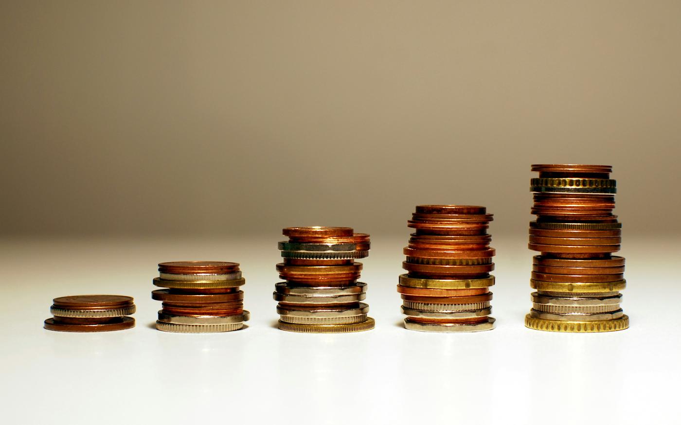 Stacks of coins increasing in height from left to right. by Kamil courtesy of Unsplash.