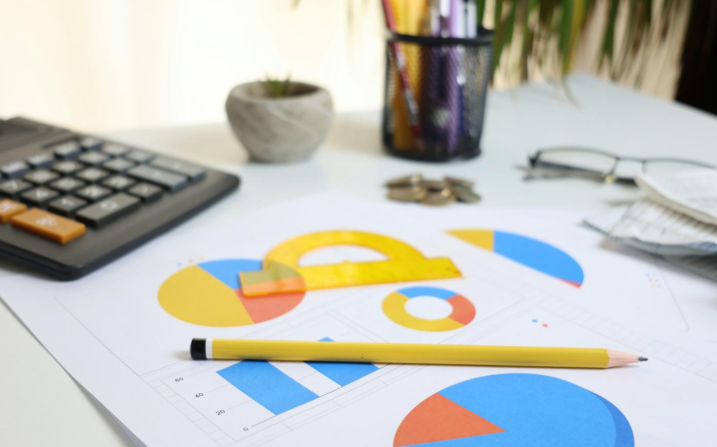 Desk with calculator, charts, and pencil by Cht Gsml courtesy of Unsplash.