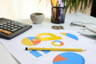 Desk with calculator, charts, and pencil by Cht Gsml courtesy of Unsplash.