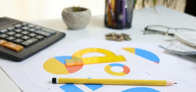 Desk with calculator, charts, and pencil by Cht Gsml courtesy of Unsplash.
